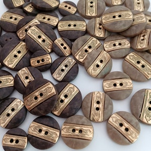 May include: A collection of brown and gold decorative buttons with a patterned design. The buttons have two holes and are made of a smooth, polished material.