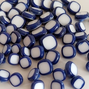 Peut inclure: Un ensemble de boutons en céramique bleu et blanc. Les boutons sont ronds avec un centre blanc et une bordure bleue.