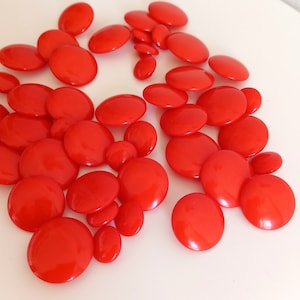 Può includere: Un grande gruppo di bottoni rotondi di colore rosso brillante. I bottoni sono lisci e lucidi.