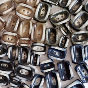 May include: A collection of assorted buttons made from natural materials, featuring a variety of colours and patterns. The buttons are rectangular and have two holes.