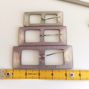 the buckles are photographed next to a tape measure
Three available size