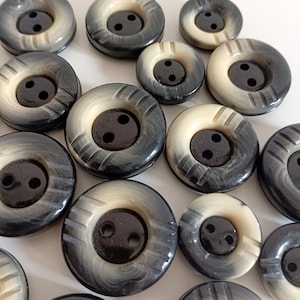 May include: Assortment of black and white buttons with two holes. The buttons have a raised design and a glossy finish.