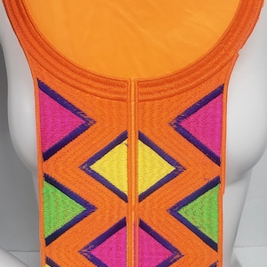 May include: Orange fabric with a circular cutout and a geometric pattern of pink, yellow, green, and blue triangles. The fabric is embroidered with a dark blue outline.