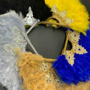 Puede incluir: Cuatro abanicos de plumas con adornos decorativos. Los abanicos son de color negro, amarillo, plateado y azul.