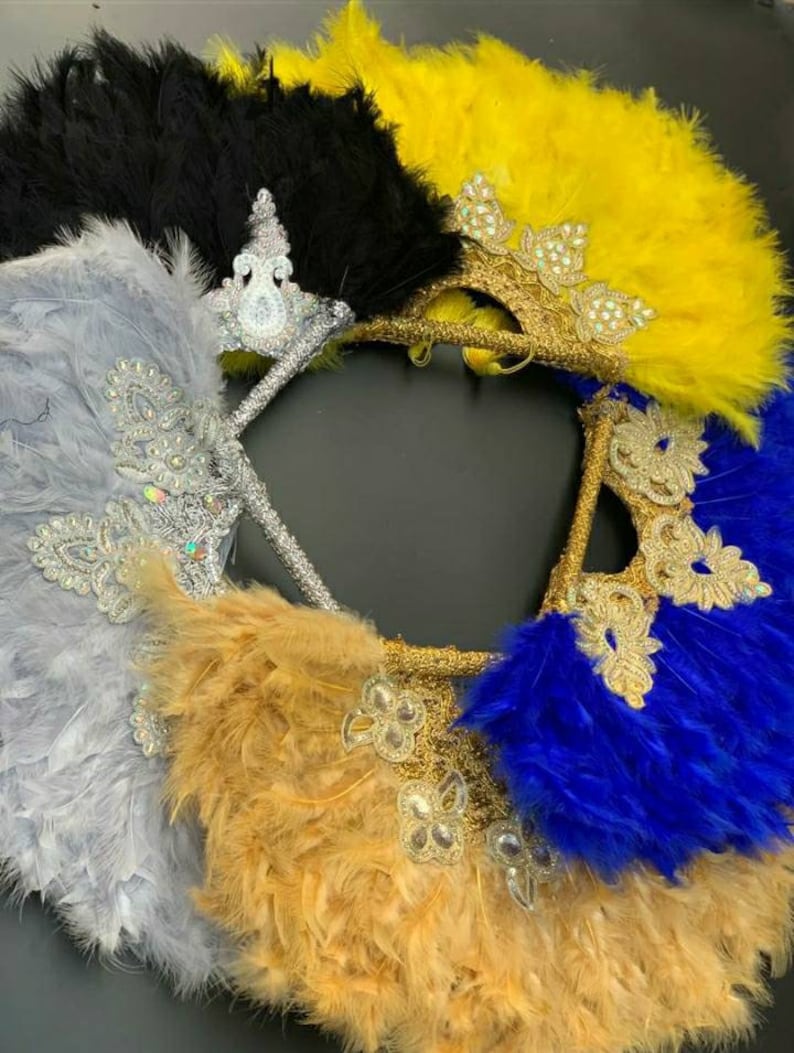 Puede incluir: Cuatro abanicos de plumas con adornos decorativos. Los abanicos son de color negro, amarillo, plateado y azul.