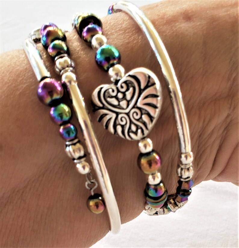 May include: A silver bracelet set with a heart charm and iridescent beads.