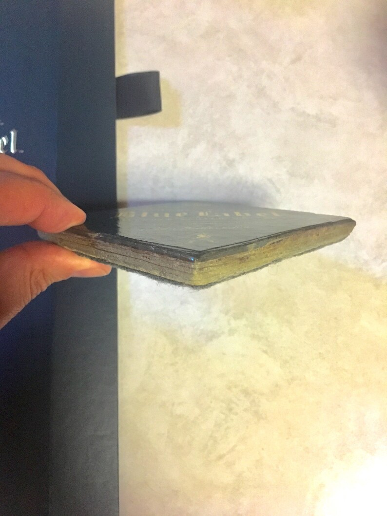 May include: Close-up of the spine of a hardback book with a black cover and gold lettering. The book is slightly worn and has a few scratches.