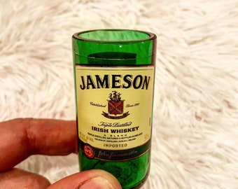May include: A green glass shot glass with a Jameson Irish Whiskey label. The label features the Jameson logo, the words "Triple Distilled Irish Whiskey", "A Blend", and "Imported".