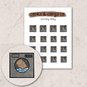 May include: A sheet of stickers featuring a cartoon illustration of a washing machine with a cork inside. The text "corks & corgs co" and "laundry corky" is printed on the sheet.