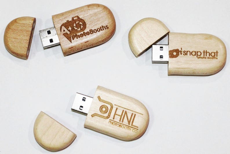 May include: Three wooden USB flash drives with different company logos engraved on them. The logos are "A+ PhotoBooths", "It's Snap That Photo Booths", and "HNL PhotoBooth Co."