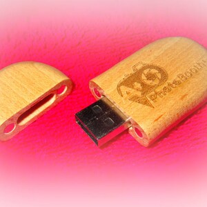 May include: A wooden USB flash drive with a photo booth logo engraved on the front. The drive is open, revealing the USB connector.