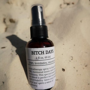 May include: A brown glass bottle with a black spray nozzle and a white label that reads "BITCH DAYS 2 fl oz, 60 ml PMS, Irritibility, moodiness Aromatherapy spray to help with PMS, hormonal issues and overall bitchiness. This special essential oil blend is perfect for moodiness and irritability. Gives your body, mind and spirit a sense of harmony."