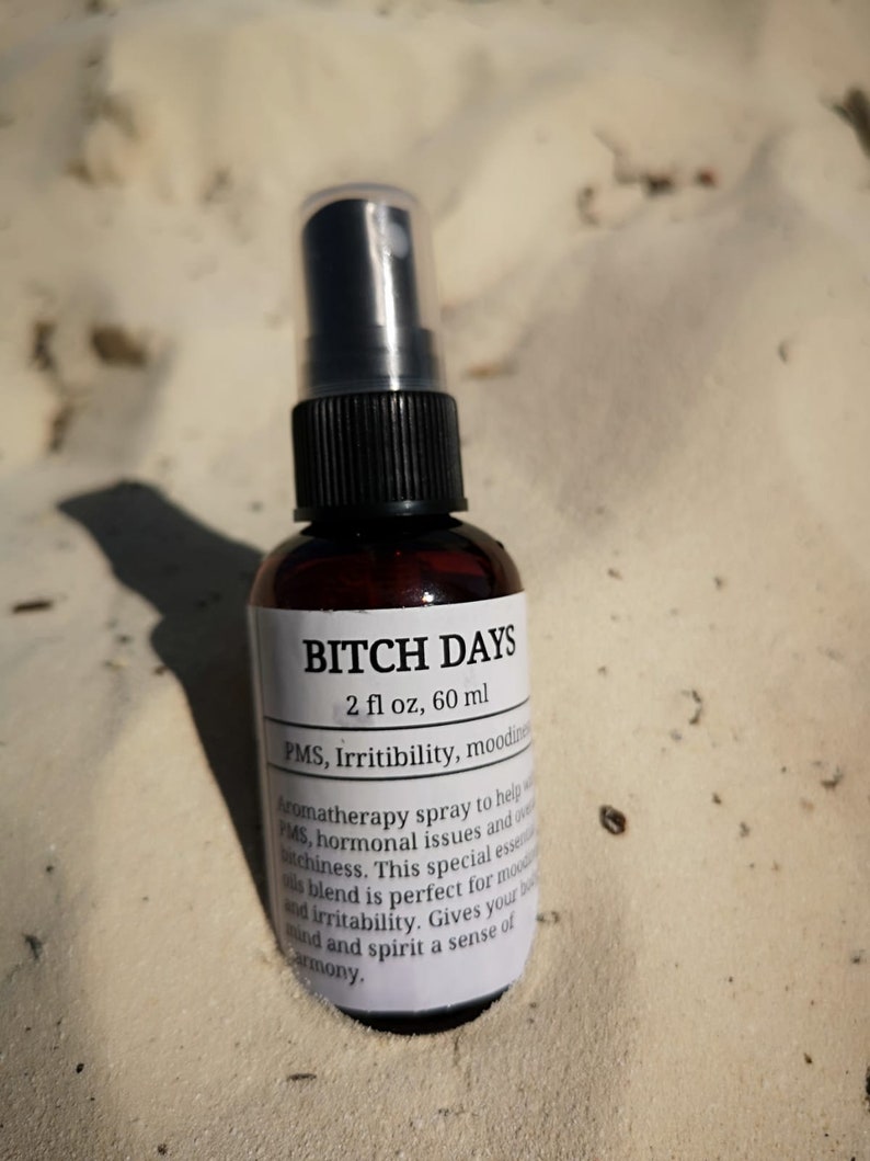May include: A brown glass bottle with a black spray nozzle and a white label that reads "BITCH DAYS 2 fl oz, 60 ml PMS, Irritibility, moodiness Aromatherapy spray to help with PMS, hormonal issues and overall bitchiness. This special essential oil blend is perfect for moodiness and irritability. Gives your body, mind and spirit a sense of harmony."