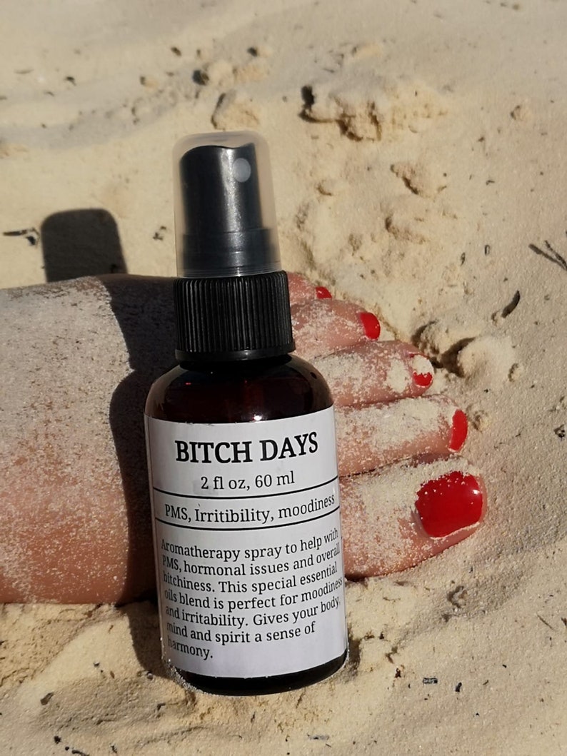 May include: A brown glass bottle with a black spray top and a white label that reads "BITCH DAYS 2 fl oz, 60 ml PMS, Irritibility, moodiness Aromatherapy spray to help with PMS, hormonal issues and overall bitchiness. This special essential oils blend is perfect for moodiness and irritability. Gives your body, mind and spirit a sense of harmony."
