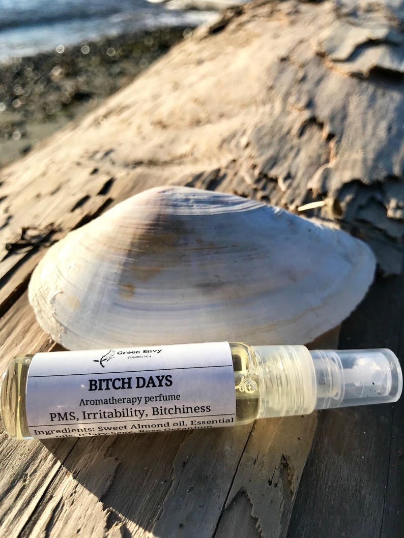May include: A small clear glass bottle with a white label that reads "BITCH DAYS Aromatherapy perfume PMS, Irritability, Bitchiness Ingredients: Sweet Almond oil, Essential"