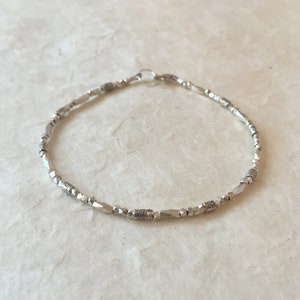 May include: A silver bracelet with small, faceted beads and a clasp.