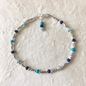 May include: A silver chain bracelet with blue and turquoise gemstone beads.