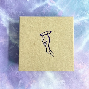 May include: A brown cardboard box with a purple angel wing design. The wing has a halo above it.