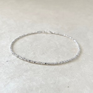 Peut inclure: Un bracelet argenté délicat composé de petites perles. Le bracelet est simple et élégant, parfait pour tous les jours.