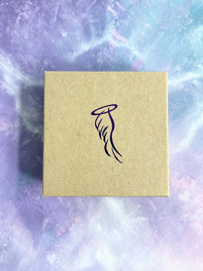 May include: A brown cardboard box with a purple angel wing design. The wing has a halo above it.