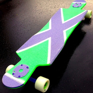 May include: A green and purple longboard skateboard with white stripes. The deck has a textured surface and the wheels are white.