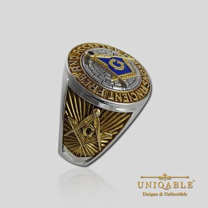 Pu&ograve; includere: Un anello massonico in argento e oro con un designo di compasso e squadra blu e oro. L'anello presenta le parole "Ancient Free and Accepted Masons" intorno al compasso e alla squadra.
