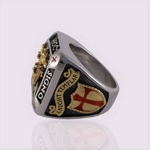 Puede incluir: Un anillo de plata con un dise&ntilde;o negro y dorado. El anillo presenta una cruz roja y las palabras "Knight Templar" y "Signo" en la banda.