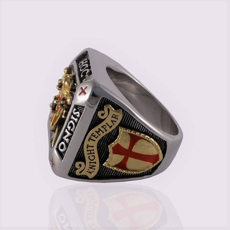 Puede incluir: Un anillo de plata con un dise&ntilde;o negro y dorado. El anillo presenta una cruz roja y las palabras "Knight Templar" y "Signo" en la banda.