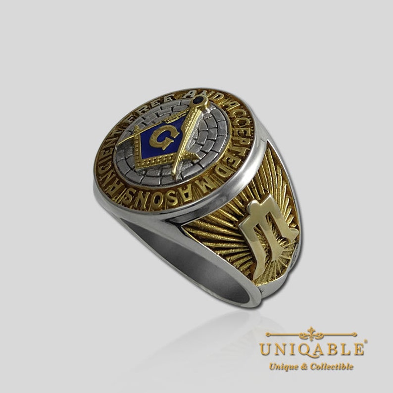 Pu&ograve; includere: Un anello massonico in argento e oro con un simbolo massonico blu e oro sulla parte superiore e le parole "Free and Accepted Masons" intorno al simbolo. Il lato dell'anello presenta un simbolo massonico dorato.