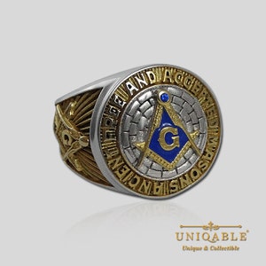 Pu&ograve; includere: Un anello massonico in argento e oro con un emblema di compasso e squadra blu e oro. L'anello &egrave; inciso con le parole "Ancient Free and Accepted Masons".