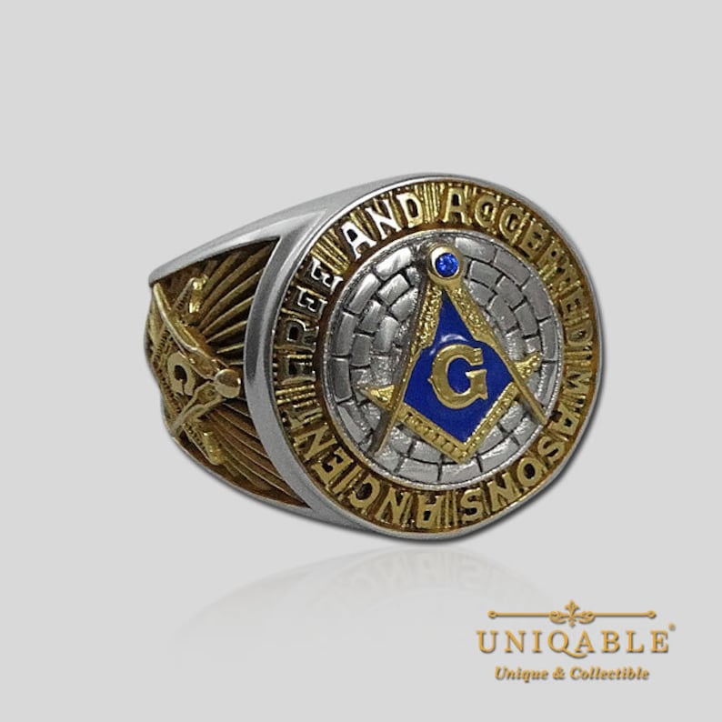 Pu&ograve; includere: Un anello massonico in argento e oro con un emblema di compasso e squadra blu e oro. L'anello &egrave; inciso con le parole "Ancient Free and Accepted Masons".