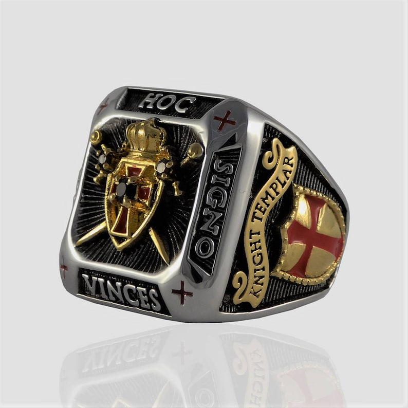 Puede incluir: Un anillo de plata y oro con un dise&ntilde;o de esmalte negro que presenta un escudo con una cruz roja, dos espadas y una corona. El anillo tambi&eacute;n tiene las palabras "HOC SIGNO VINCES" y "KNIGHT TEMPLAR" inscritas en &eacute;l.