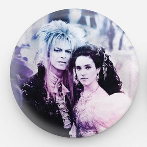 Könnte beinhalten: Ein Knopf im Vintage-Stil mit einem Schwarzweißbild eines Mannes und einer Frau aus dem Film Labyrinth. Der Mann hat langes, lockiges Haar und trägt einen dunklen Anzug. Die Frau hat langes, dunkles Haar und trägt ein weißes Kleid. Der Hintergrund ist ein weiches, verschwommenes Bild eines Waldes.