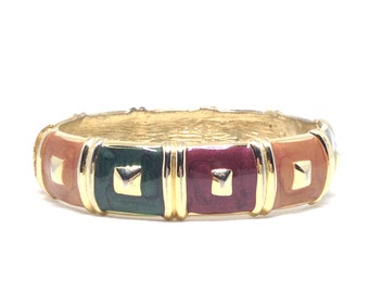 May include: Gold bangle bracelet with a multi-coloured enamel design. The bracelet features four square sections with a raised centre, each section is a different colour: orange, green, burgundy, and orange.