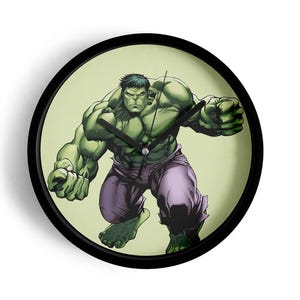 May include: A round wall clock with a black frame featuring the Hulk. The Hulk is depicted in a dynamic pose, with green skin, purple pants, and black hair. The clock face has a light green background and black clock hands.