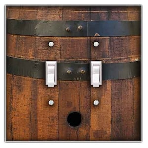 May include: A light switch cover with a rustic wood grain design. The cover features two toggle switches and a small hole in the center. The wood grain is dark brown with black metal accents.