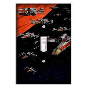 May include: A light switch cover featuring a Star Wars X-Wing fighter squadron flying through space. The X-Wings are white with red and orange stripes. The background is a dark blue space with stars and a red planet.