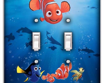 Könnte beinhalten: Ein hellblauer Doppel-Lichtschalter mit einer farbenfrohen Unterwasserszene mit Nemo, Dory und einer Schildkröte. Die Szene enthält die Farben Blau, Orange, Gelb und Grün.