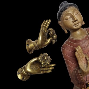 Puede incluir: Dos tiradores de puerta de metal dorado en forma de mano con un diseño floral. Los tiradores están en posición de oración con las palmas hacia arriba.