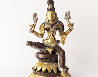 May include: A gold and brown metal statue of a seated Hindu deity with a lotus base. The deity has a crown and is adorned with jewelry.