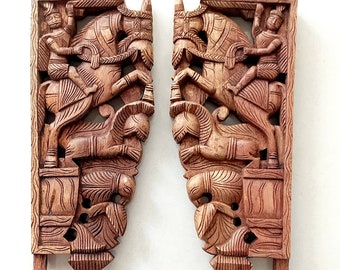 May include: Two intricately carved wooden wall brackets, each featuring a warrior riding a horse, with a smaller figure kneeling below. The brackets are a rich brown color and have a detailed, ornate design.