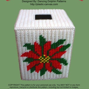 May include: A white plastic tissue box cover with a red poinsettia design. The box cover is decorated with a red poinsettia flower with green leaves and a yellow center. The text "Christmas Poinsettia Boutique Tissue" is at the top of the image. The text "Designed By: Dancing Dolphin Patterns" is below the image. The text "http://plastic-canvas.com" is below the previous text. The text "COPYRIGHT This pattern is for your personal use only. You MAY NOT in any form reproduce, transmit or distribute this pattern, including but not limited to images, diagrams and text through any venue, including but not limited to photocopying, other electrical or mechanical means, recording, or any other information storage and or retrieval system. Copyright © 2018 Dancing Dolphin Patterns" is at the bottom of the image.