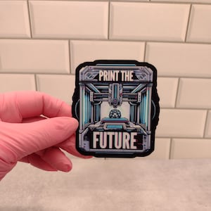 May include: A black and white sticker with a 3D printer design and the text "Print the Future".