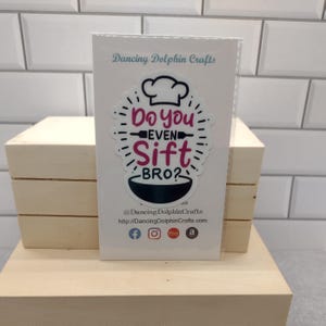 May include: White card with a black and white sticker that says "Do you even sift bro?" with a chef's hat and a rolling pin. The sticker is on a white background with black text that says "Dancing Dolphin Crafts" and a website address.