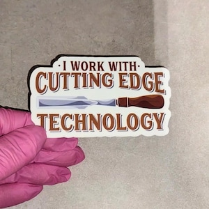May include: White sticker with brown text that reads "I work with cutting edge technology". A cartoon image of a chisel is above the text.