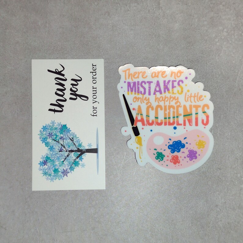 Puede incluir: Una tarjeta de agradecimiento con un dise&ntilde;o de &aacute;rbol de copo de nieve azul y el texto "gracias por su pedido". Una pegatina con una paleta de pintura y el texto "No hay errores, solo peque&ntilde;os accidentes felices" en rosa, morado y verde.
