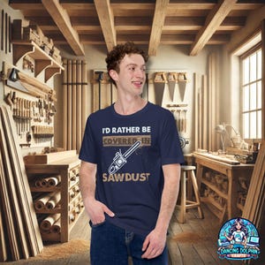 K&ouml;nnte beinhalten: Ein marineblaues T-Shirt mit einer wei&szlig;en Grafik, auf der "Ich w&auml;re lieber mit S&auml;gemehl bedeckt" steht. Die Grafik enth&auml;lt auch eine Kettens&auml;ge.
