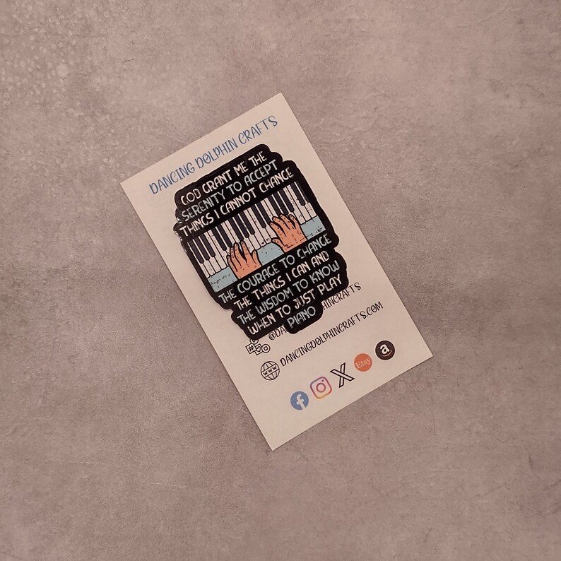 May include: A colorful enamel pin featuring a piano with hands playing. The pin has a quote that reads: "God grant me the serenity to accept things I cannot change, the courage to change the things I can and the wisdom to know when to just play piano."