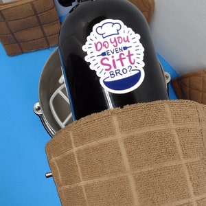May include: A black stand mixer with a white bowl and a sticker that says "Do you even sift bro?" on the side.