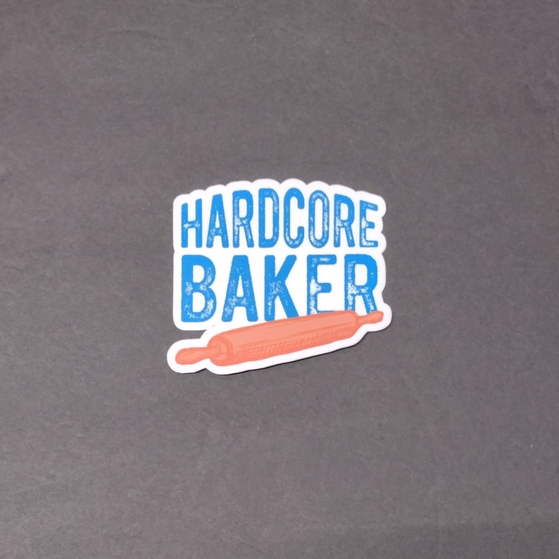 May include: A blue and white sticker with the text "HARDCORE BAKER" and a pink rolling pin.